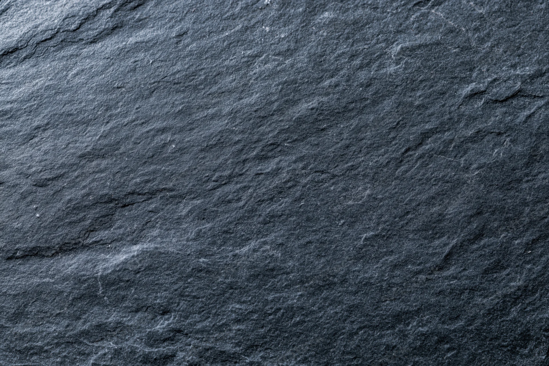 Close-up of dark slate stone surface with natural texture and cracks