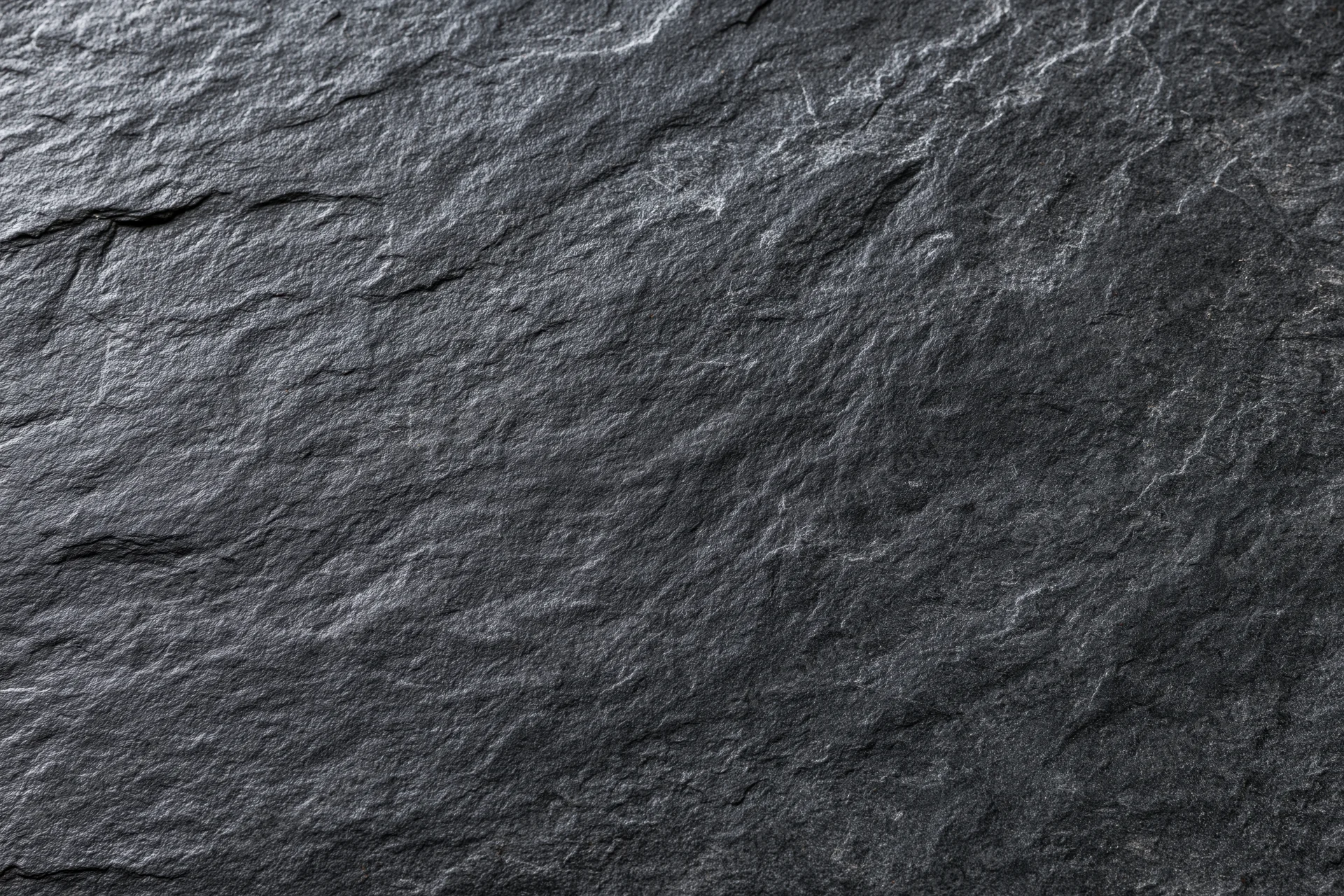 Close-up of dark slate stone surface with natural cracks and texture