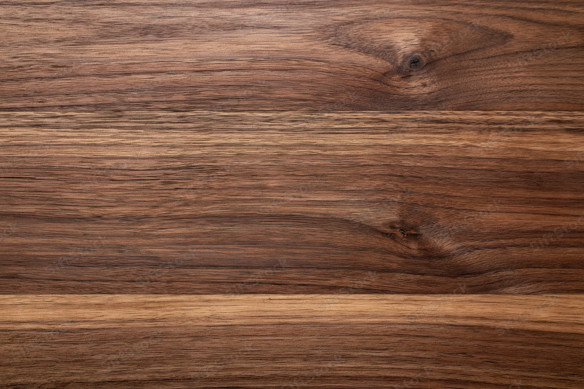 Close-up of dark walnut wood surface with visible grain and knots, flat lay view