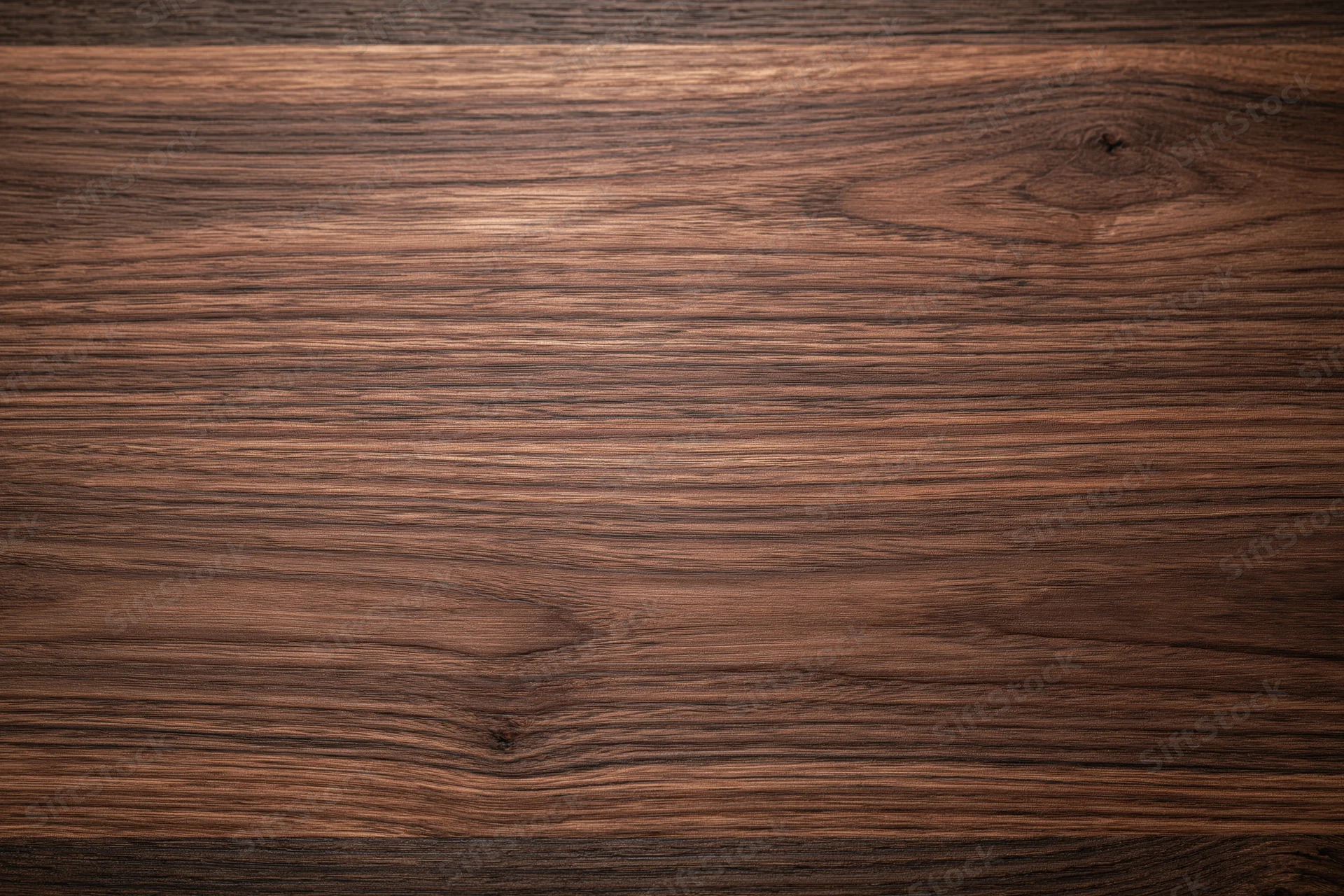 Close-up of dark walnut wood surface with visible grain and knots filling the frame