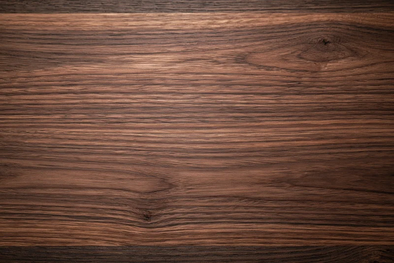 Close-up of dark walnut wood surface with visible grain and knots filling the frame