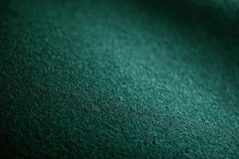Close-up of deep forest green felt fabric with visible texture and subtle shadows