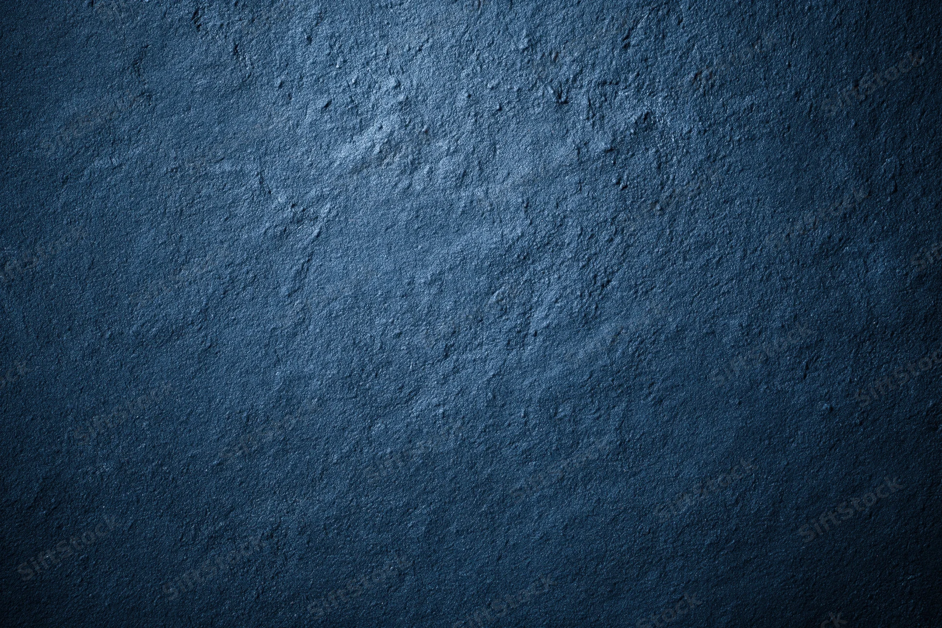 Close-up of a deep navy blue textured concrete surface with rough, uneven finish and subtle lighting gradient