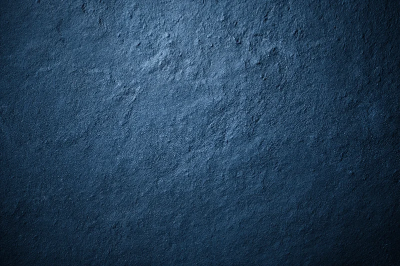Close-up of a deep navy blue textured concrete surface with rough, uneven finish and subtle lighting gradient