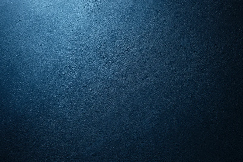 Close-up of a deep navy blue textured surface with gradient lighting and subtle vignette effect