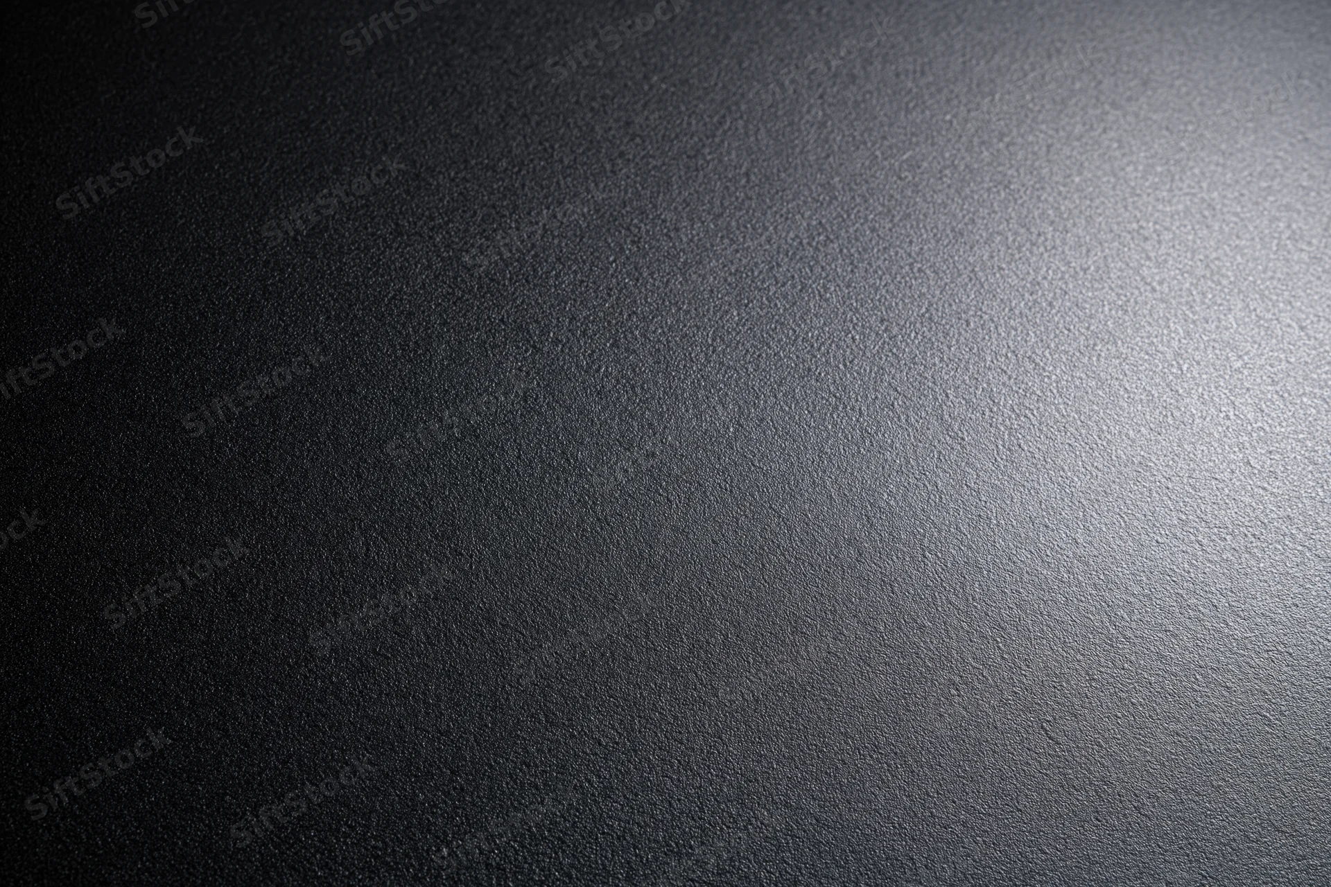 Close-up of a matte black textured surface with light gradient from right to left