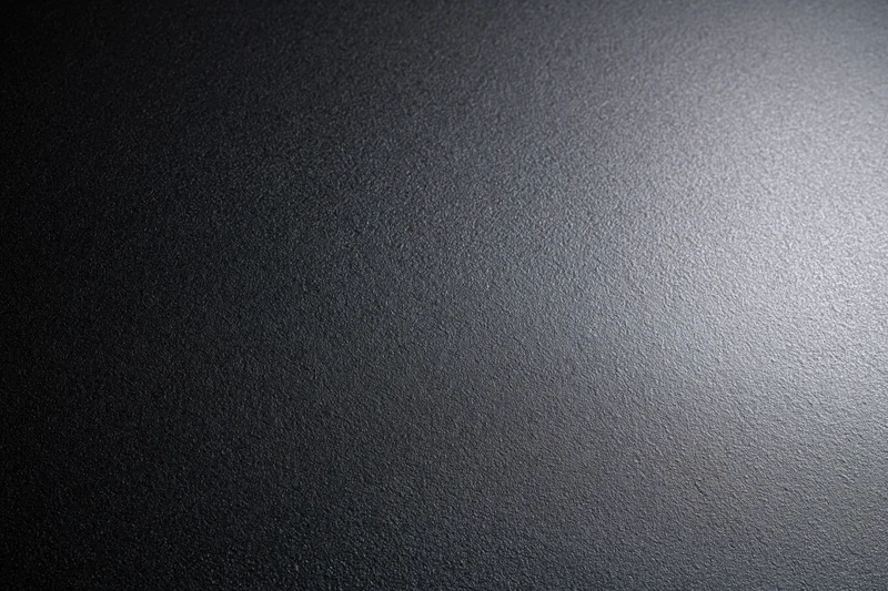 Close-up of a matte black textured surface with light gradient from right to left