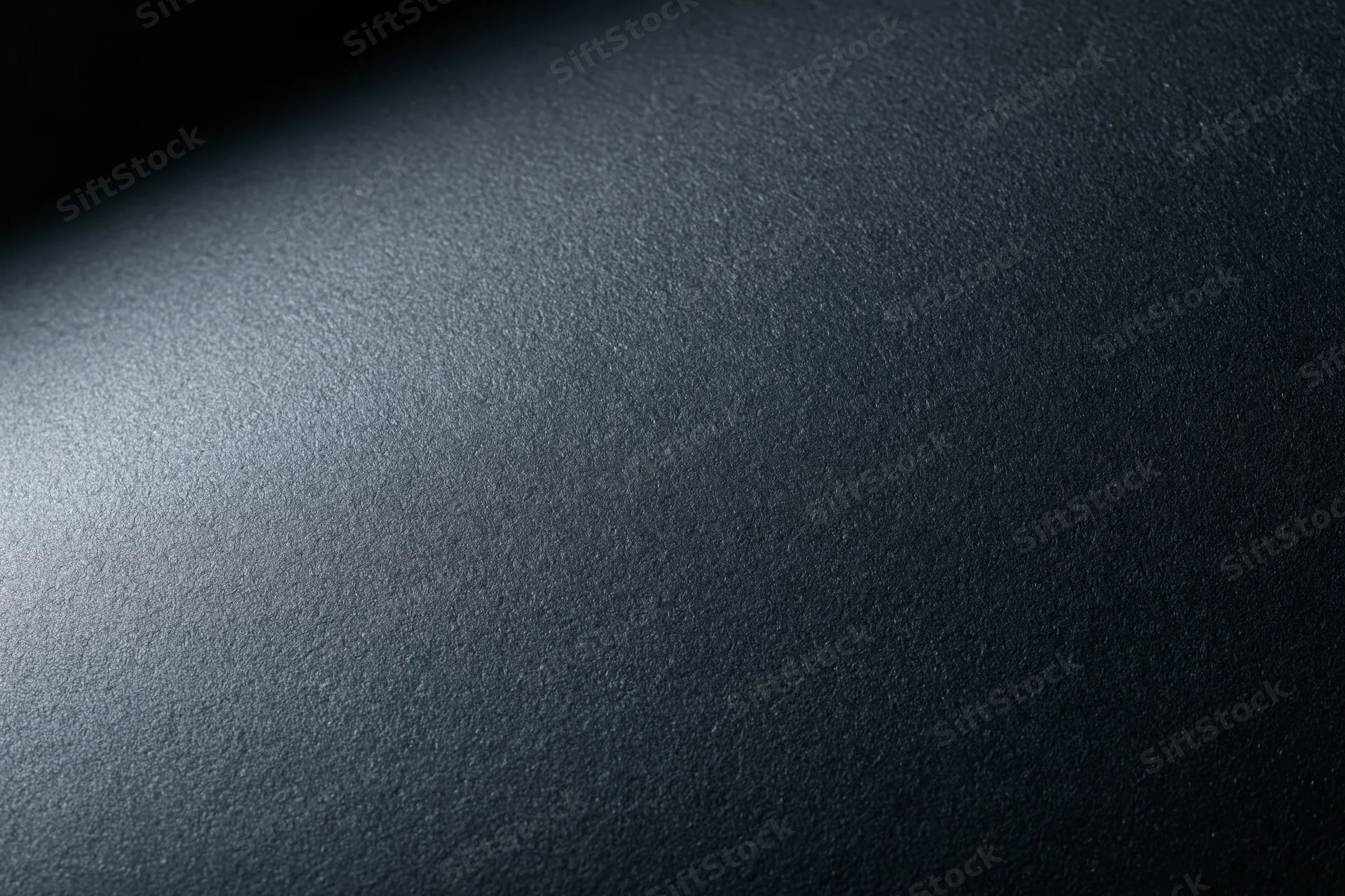 Close-up of a matte black textured surface with soft lighting gradient