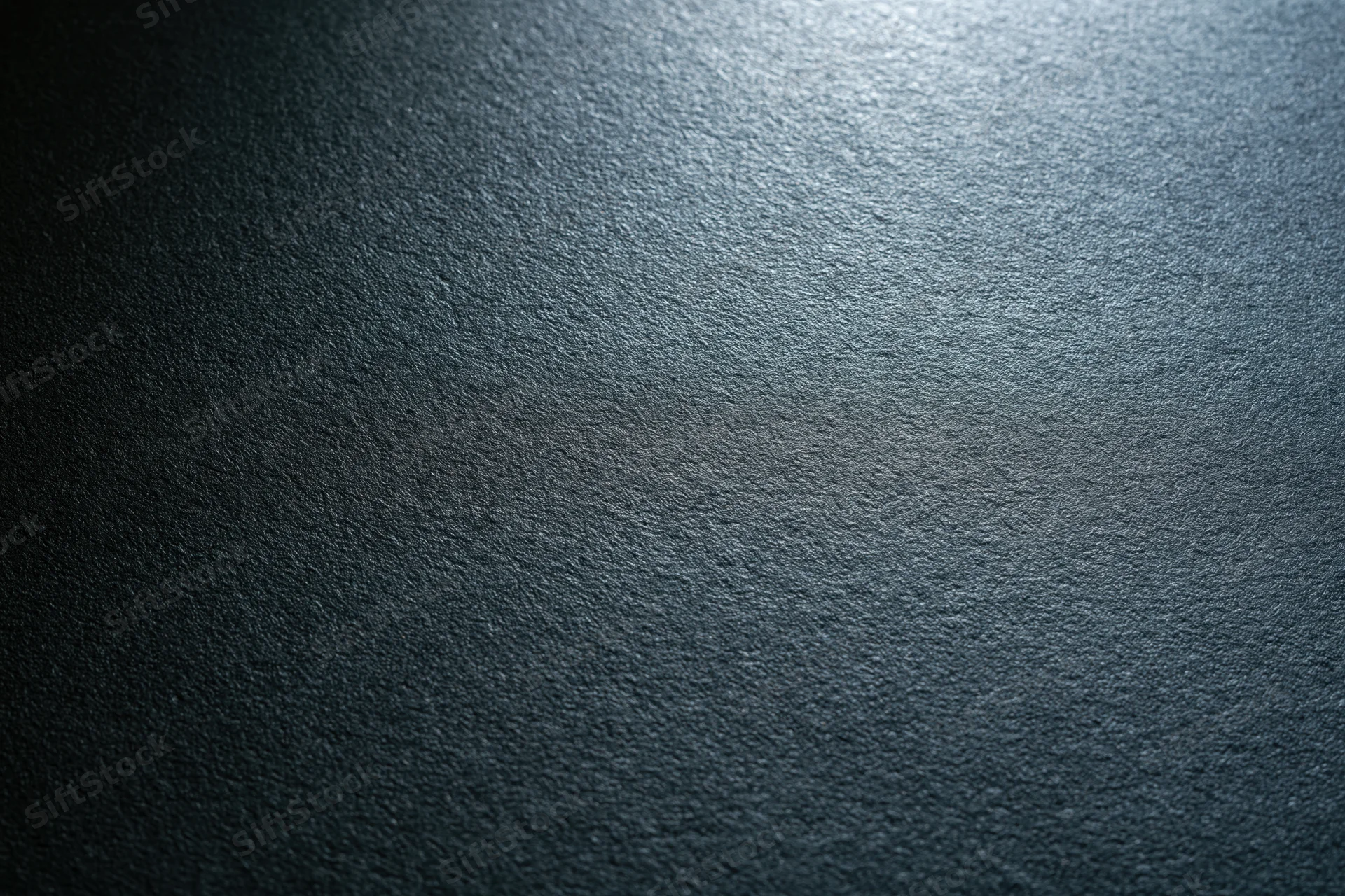 Close-up of a matte black textured surface with light gradient and subtle grain pattern