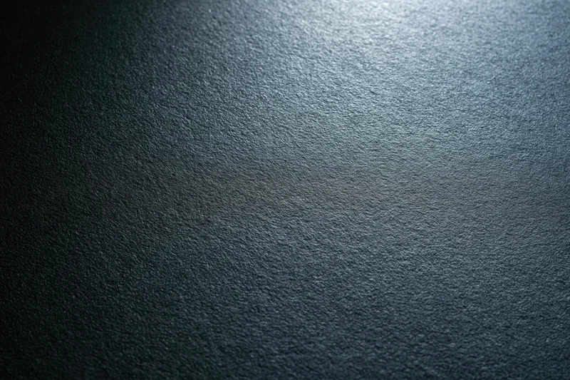 Close-up of a matte black textured surface with light gradient and subtle grain pattern