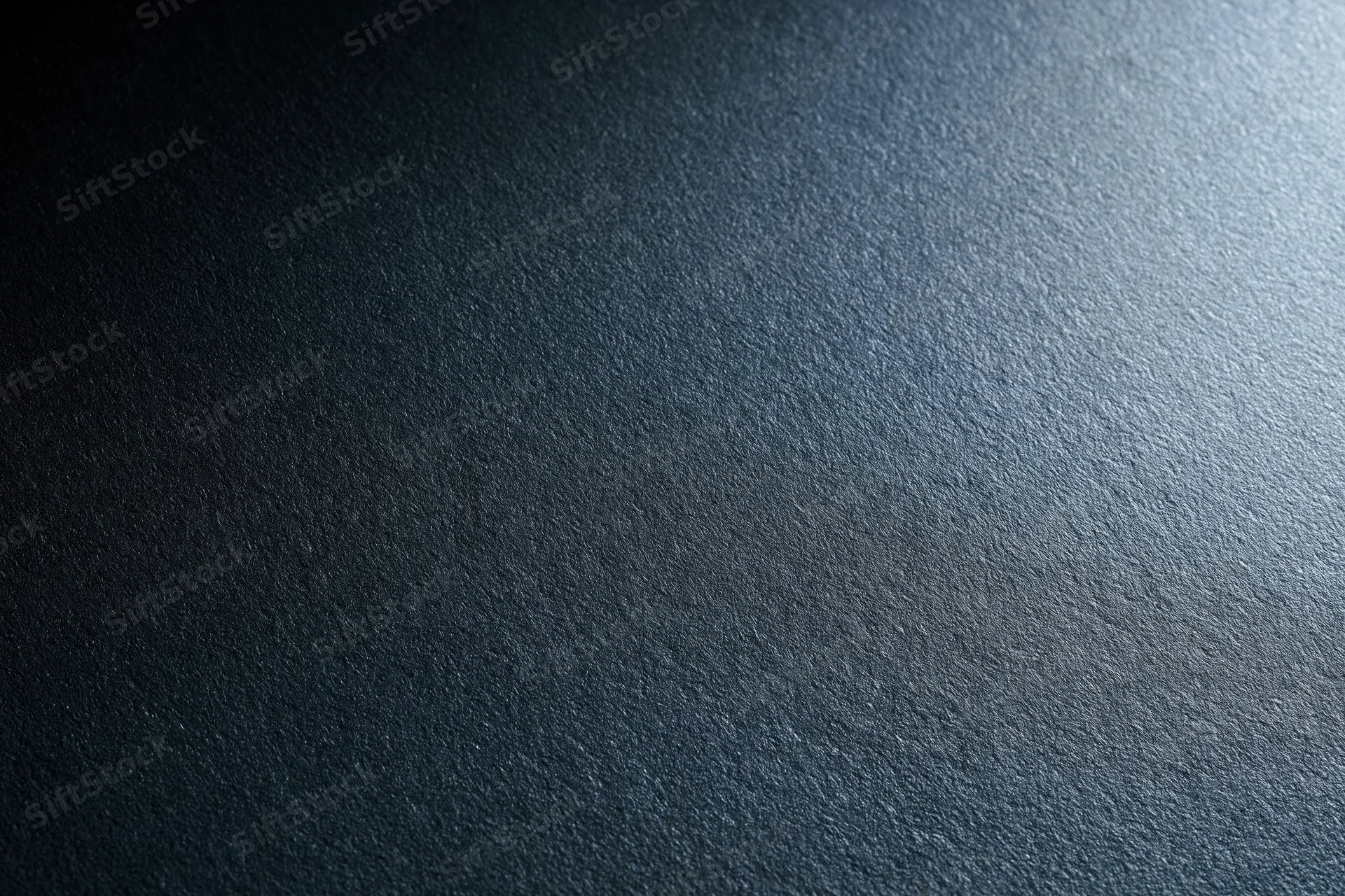 Close-up of a matte black textured surface with light gradient and subtle grain