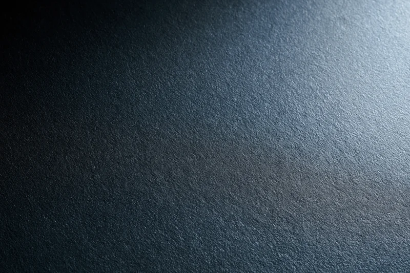 Close-up of a matte black textured surface with light gradient and subtle grain
