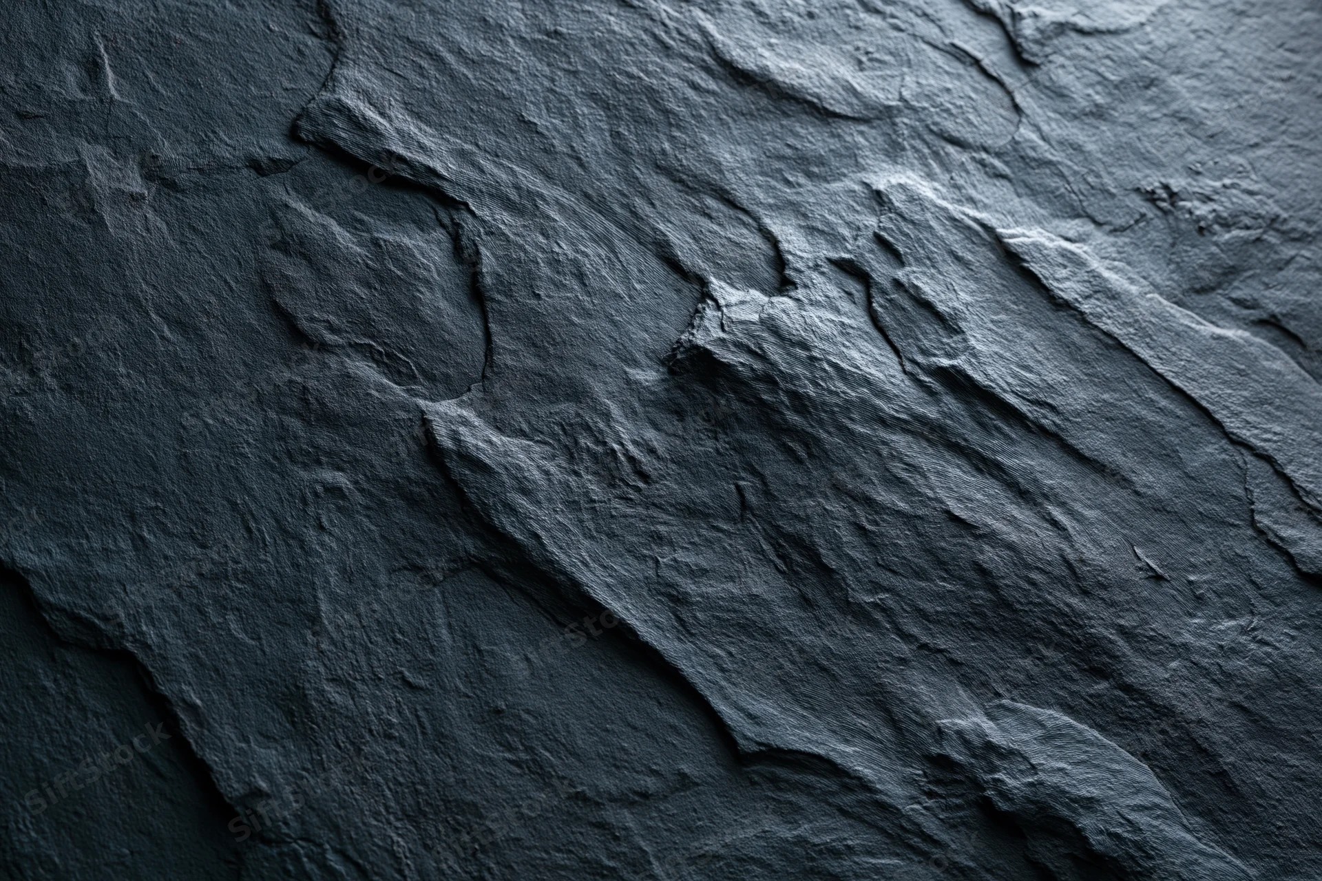 Close-up of dark rough slate surface with natural cracks and texture