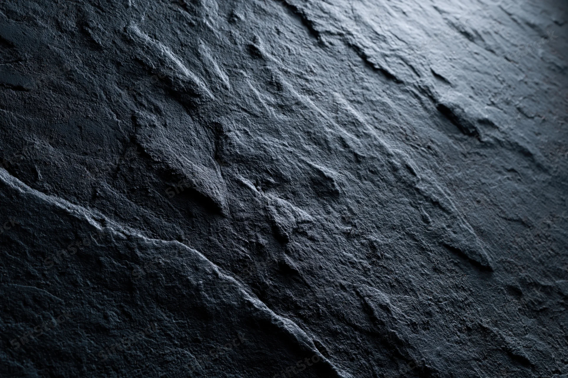 Close-up of dark rough slate surface with natural texture and striations