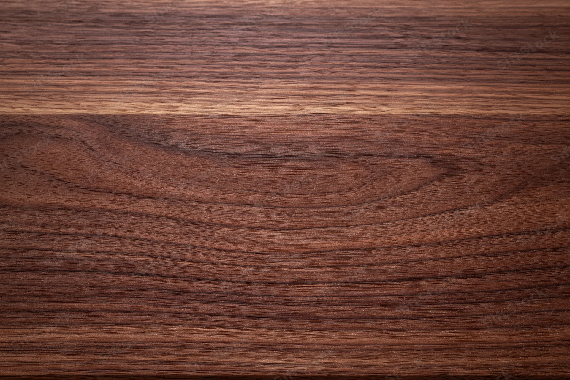 Close-up of smooth dark walnut wood surface with visible grain pattern