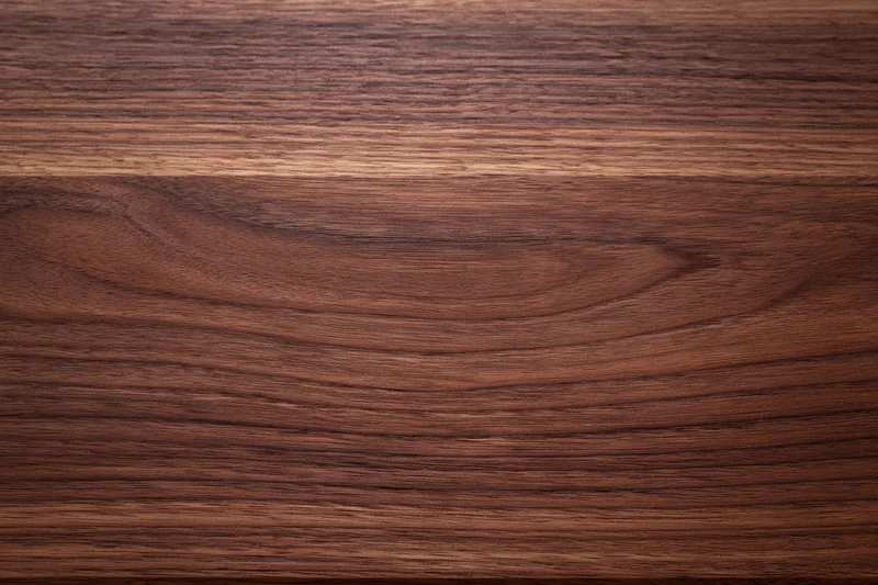 Close-up of smooth dark walnut wood surface with visible grain pattern