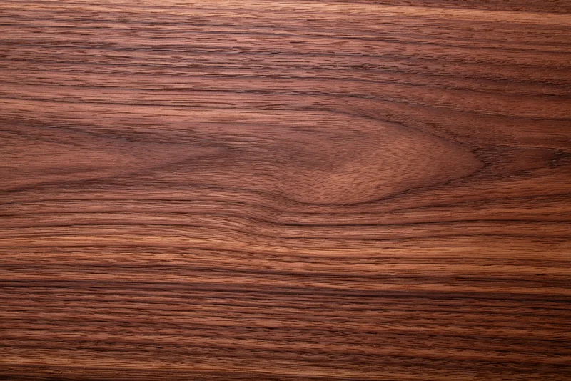 Close-up of smooth dark walnut wood surface with visible grain pattern