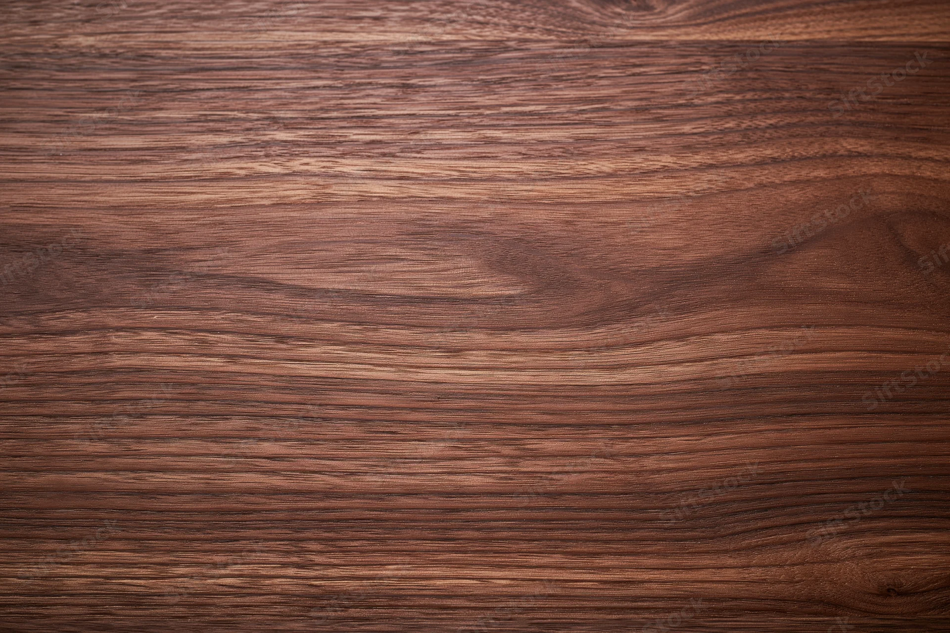 Close-up of smooth dark walnut wood surface with visible grain pattern