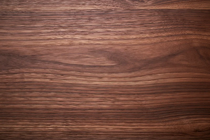 Close-up of smooth dark walnut wood surface with visible grain pattern