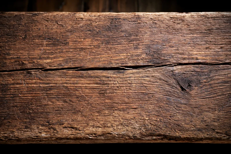 Close-up of a weathered wooden plank with visible grain and cracks filling the frame