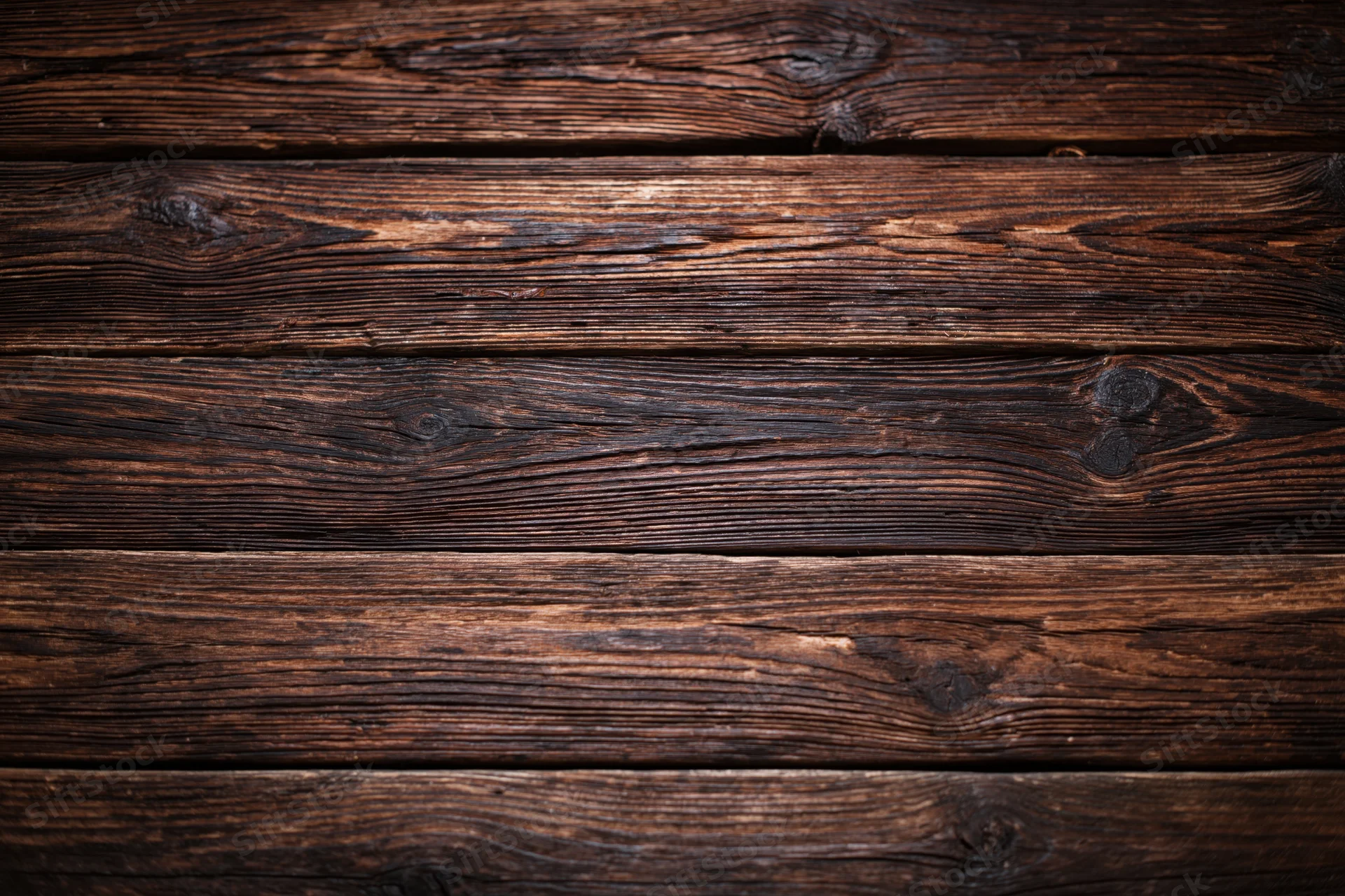 Close-up of dark aged wooden planks arranged horizontally as a textured surface