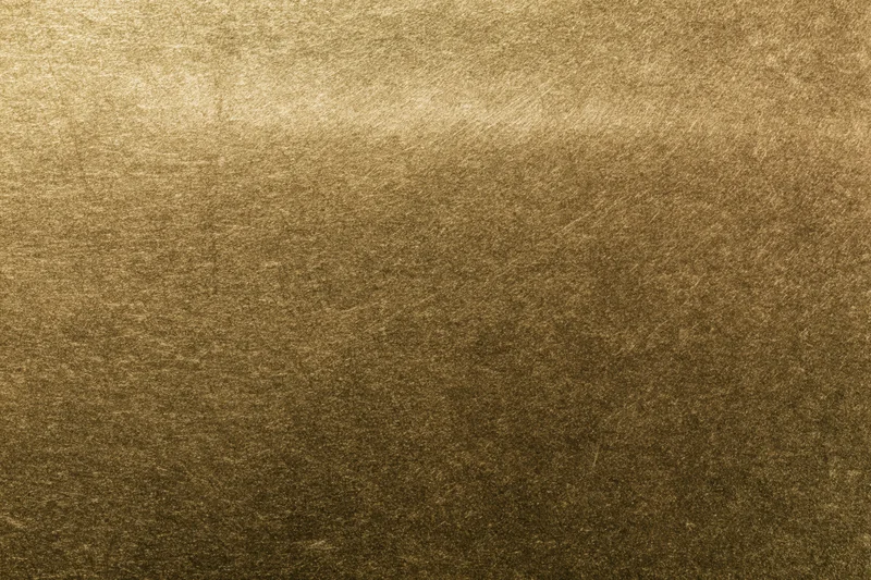 Close-up of aged brass metal surface with textured patina and warm golden tones