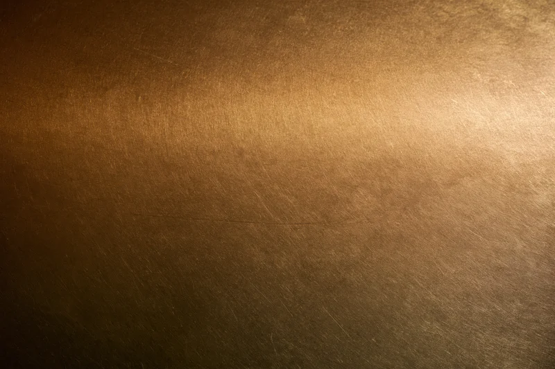 Close-up of an aged brass metal surface with visible texture and patina