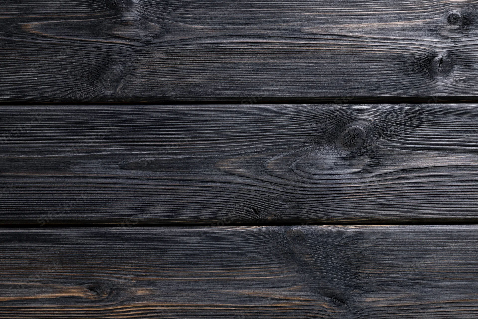 Close-up of dark charcoal-stained horizontal wooden planks with visible grain and knots
