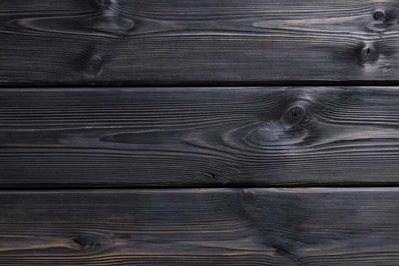 Close-up of dark charcoal-stained horizontal wooden planks with visible grain and knots