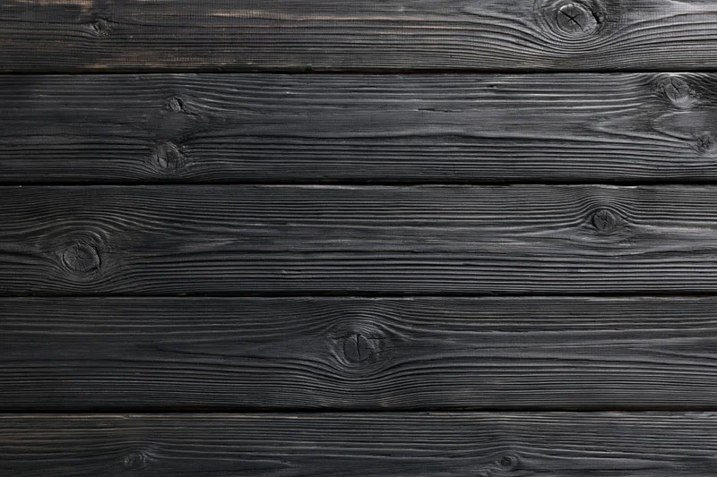 Dark charcoal-stained horizontal wooden planks with visible grain and knots forming a textured surface