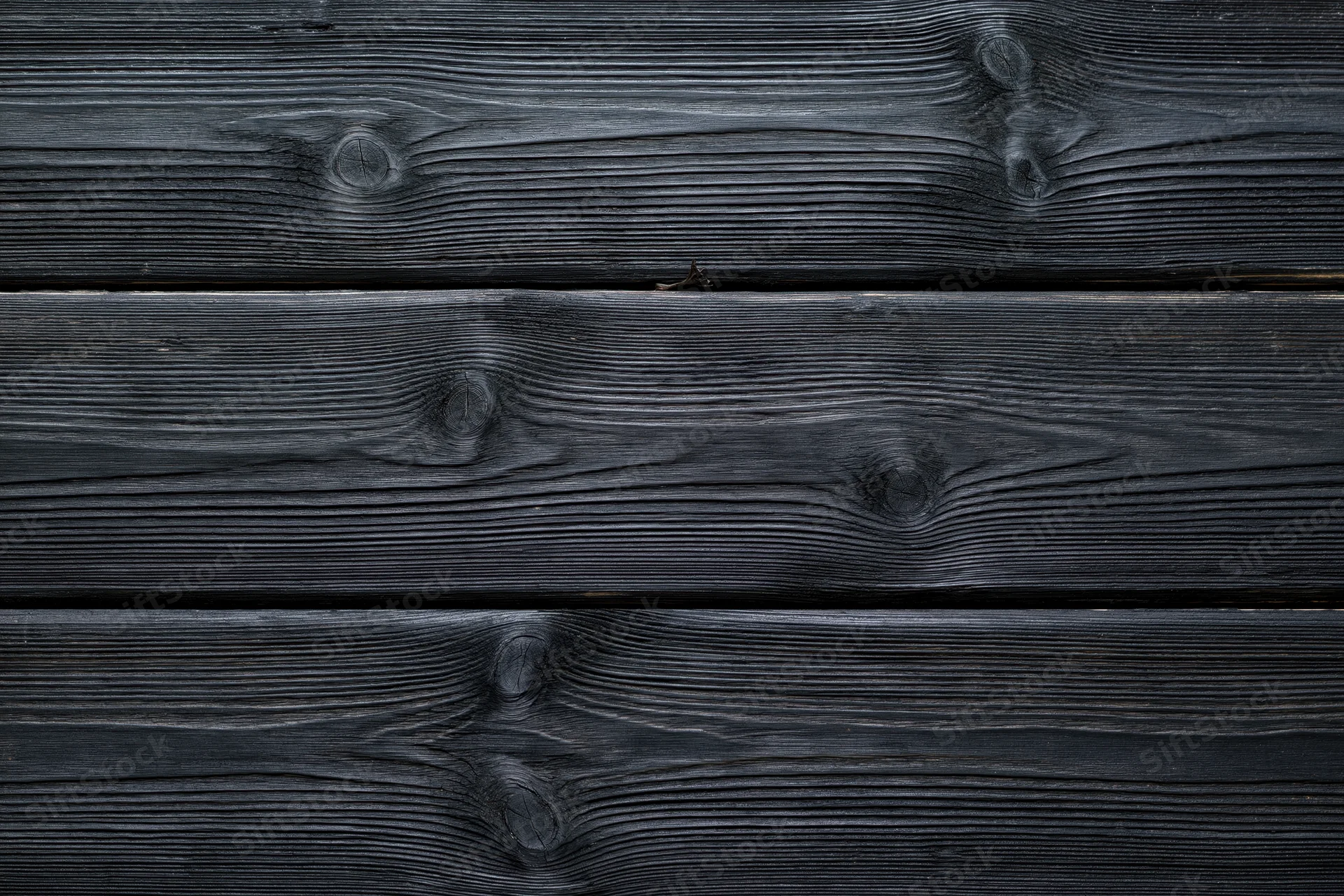 Dark charcoal-stained horizontal wooden planks with visible grain and knots forming a textured surface