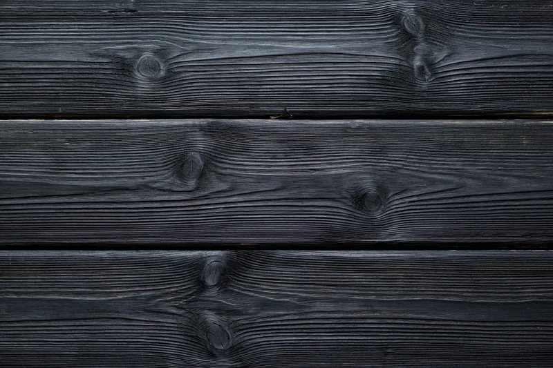 Dark charcoal-stained horizontal wooden planks with visible grain and knots forming a textured surface