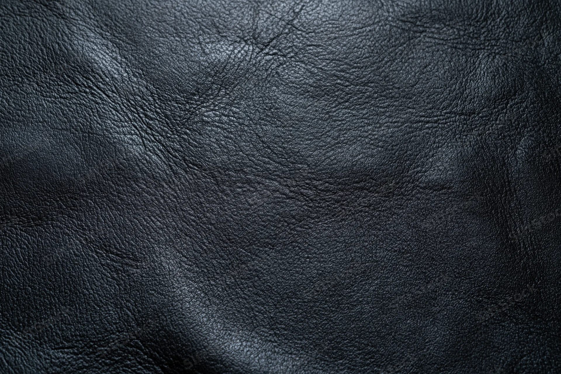 Close-up of dark charcoal black leather surface with natural grain and texture