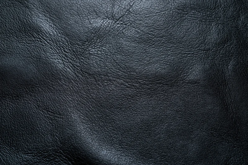Close-up of dark charcoal black leather surface with natural grain and texture