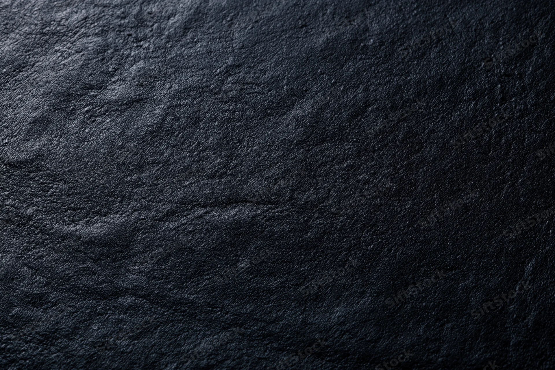 Close-up of dark charcoal black leather surface with visible grain and texture