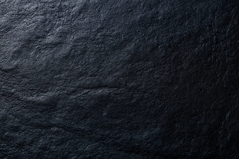 Close-up of dark charcoal black leather surface with visible grain and texture