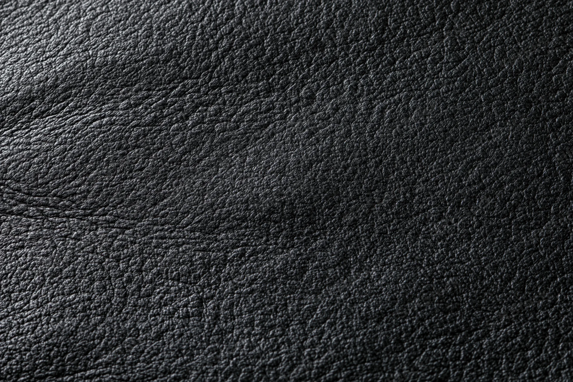 Close-up of dark charcoal black leather surface with visible grain texture