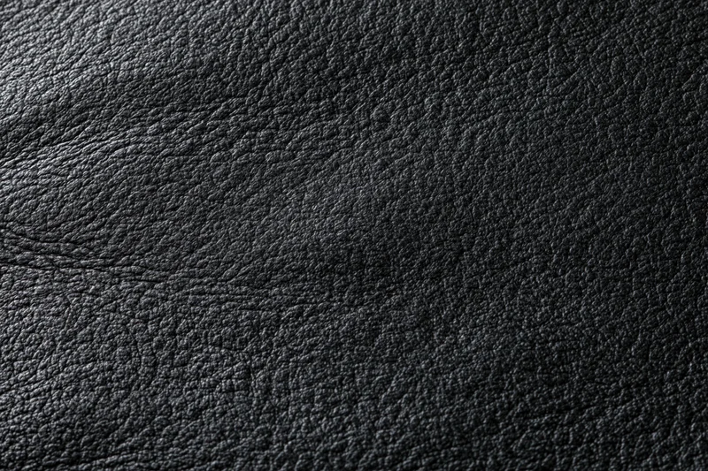 Close-up of dark charcoal black leather surface with visible grain texture