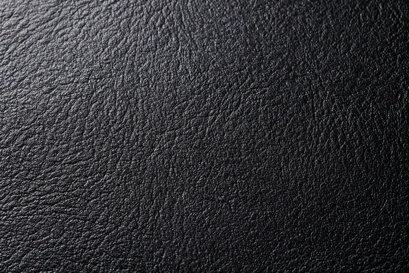 Close-up of dark charcoal black leather surface with visible grain and texture