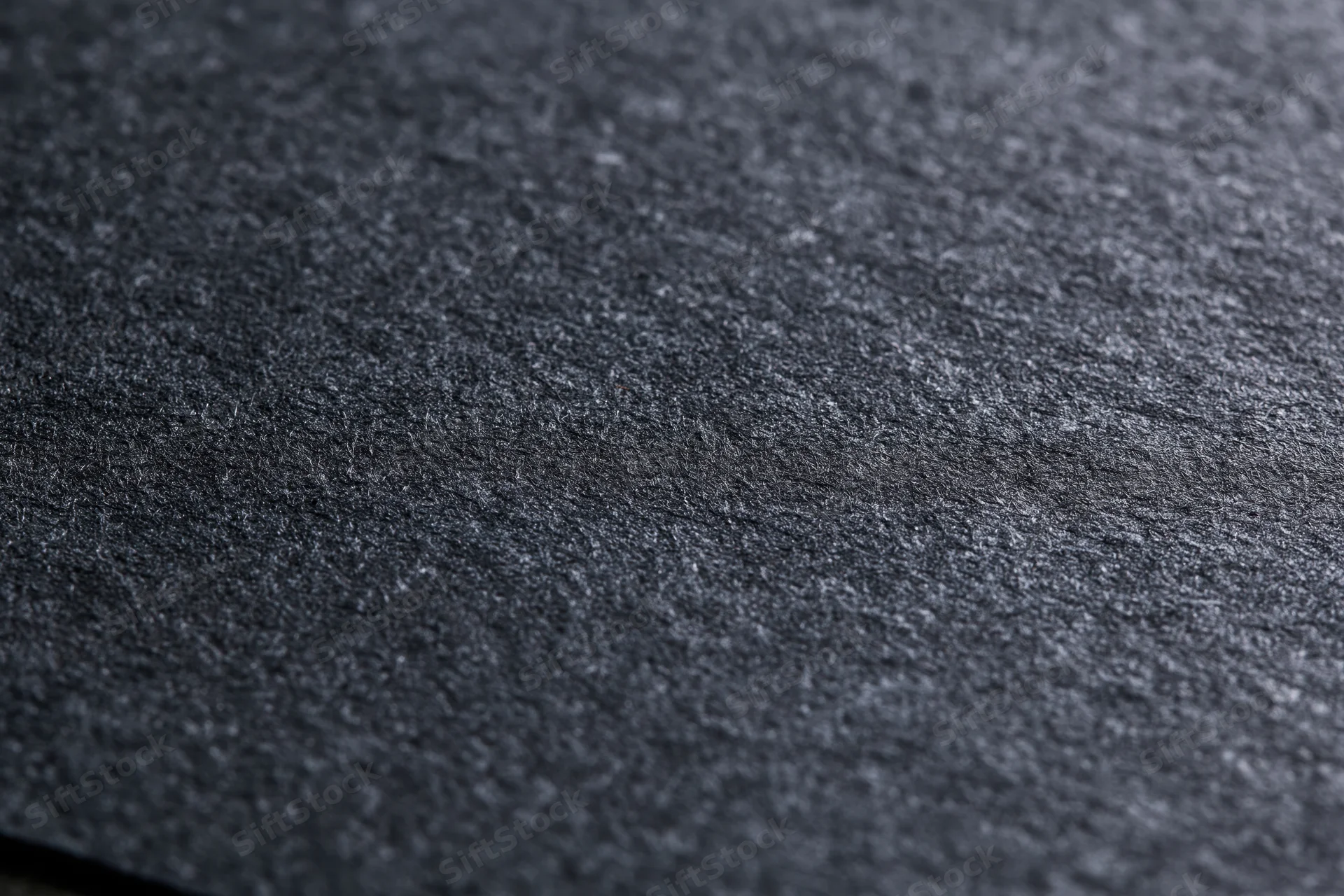 Close-up of dark charcoal black textured paper surface in flat lay arrangement
