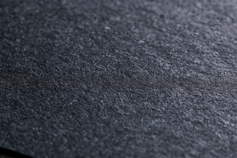 Close-up of dark charcoal black textured paper surface in flat lay arrangement