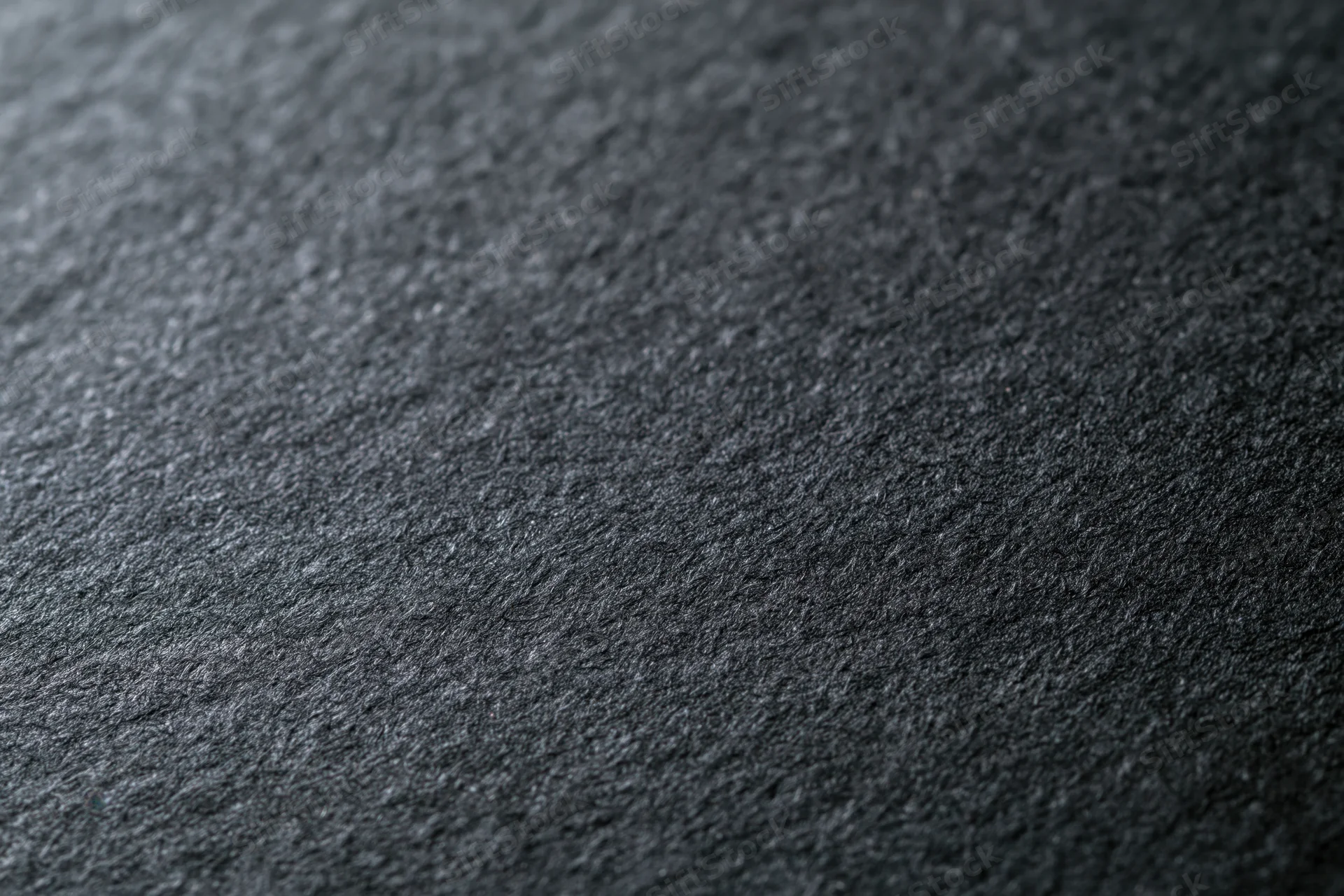 Close-up of dark charcoal black paper surface with textured grain in flat lay arrangement