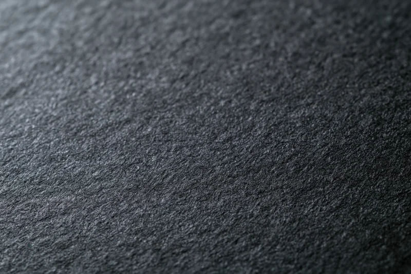 Close-up of dark charcoal black paper surface with textured grain in flat lay arrangement