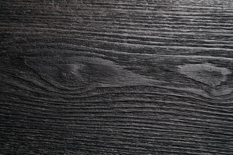 Close-up of dark charcoal wood surface showing natural grain texture
