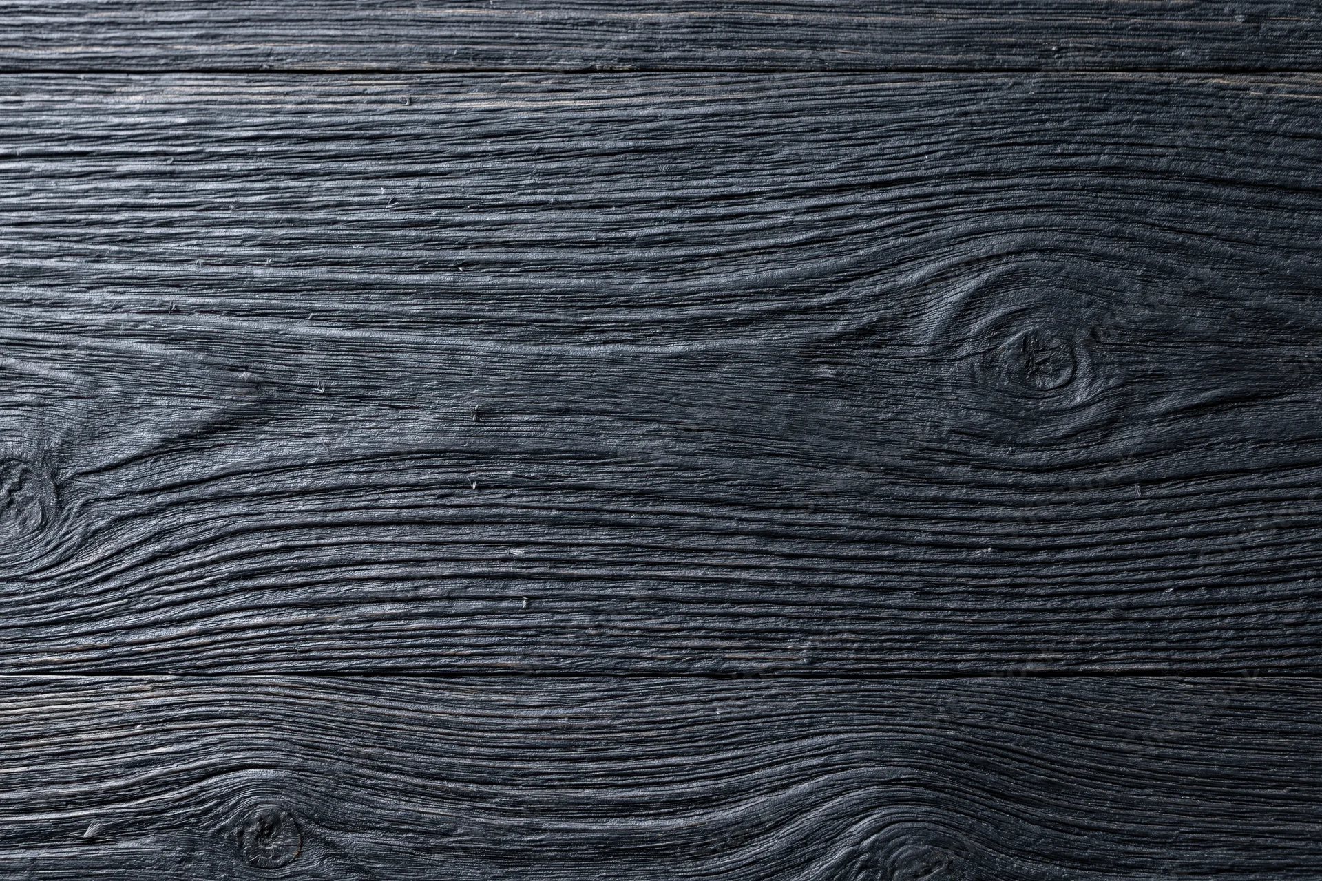 Close-up of dark charcoal wood surface showing natural grain and knots