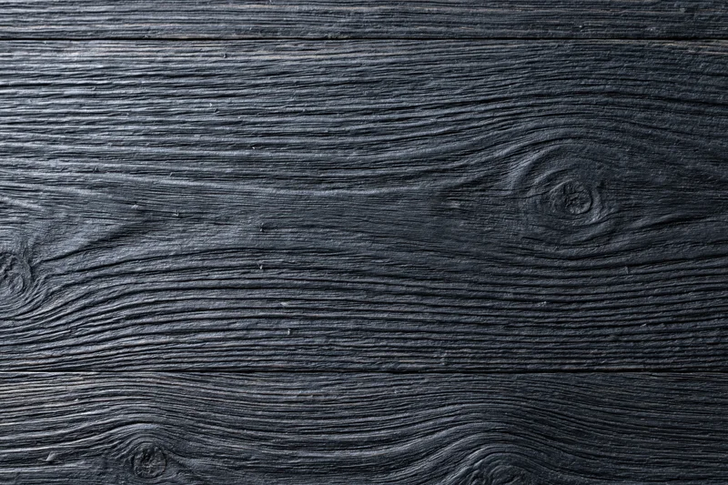 Close-up of dark charcoal wood surface showing natural grain and knots