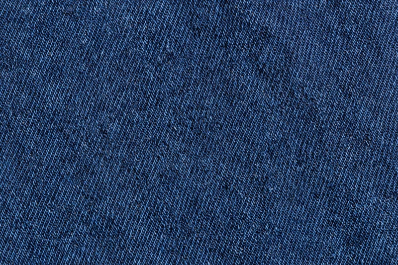 Close-up of dark indigo denim fabric with visible twill weave pattern