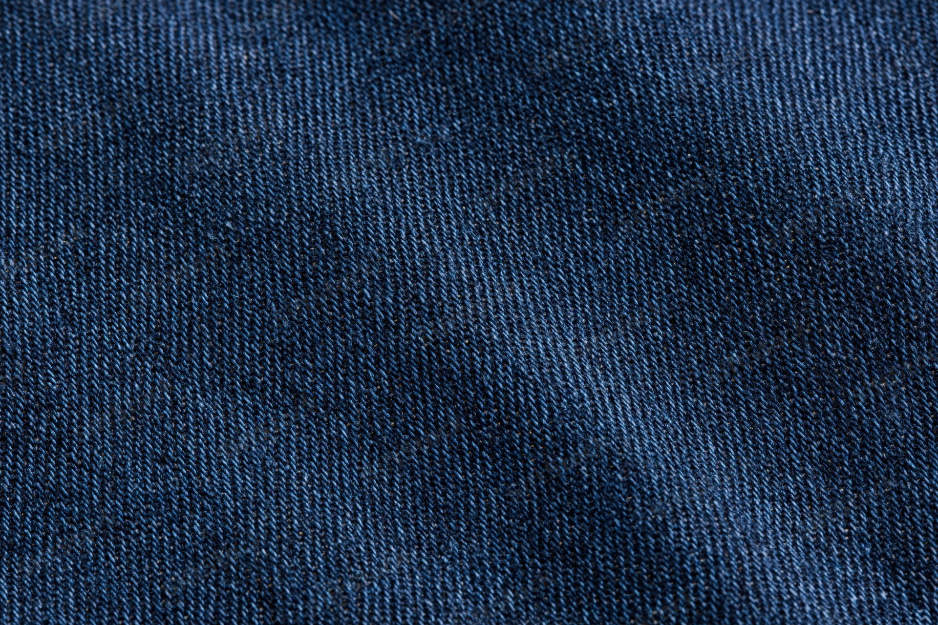 Close-up of dark indigo denim fabric with visible weave pattern filling the frame