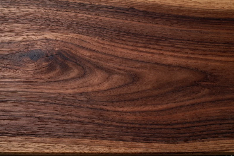 Close-up of dark walnut wood surface with visible grain and texture
