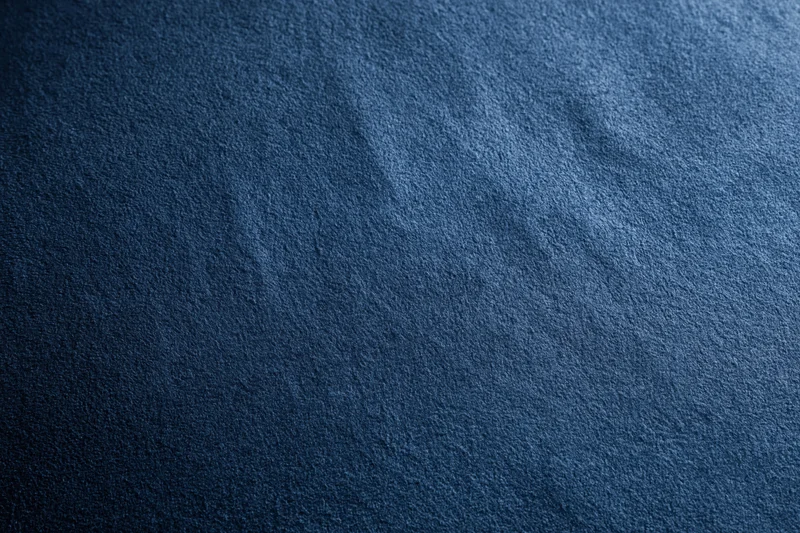 Close-up of deep navy blue suede fabric surface with visible texture and grain